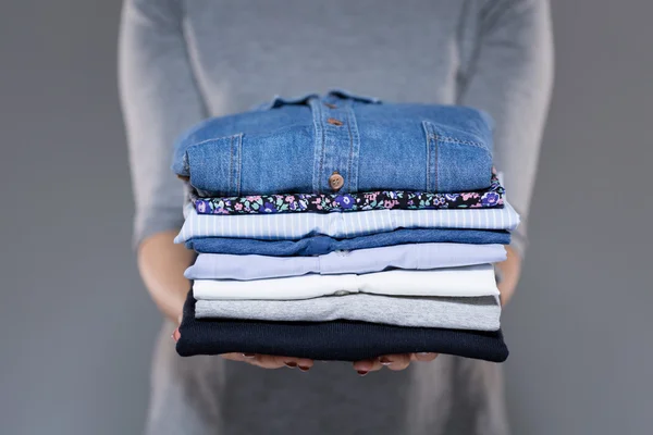 Mulher segurando roupas nas mãos — Fotografia de Stock