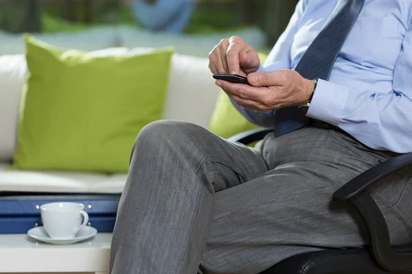 Hombre sentado en la silla y utiliza el teléfono —  Fotos de Stock