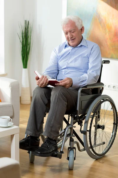 Elderly man reading book at home — Stock Photo, Image