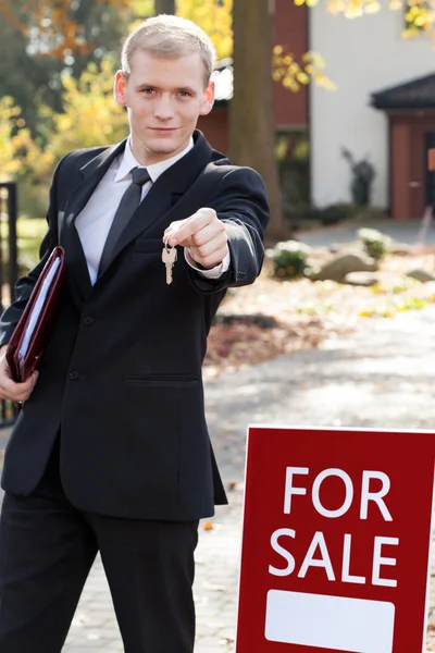 Estate agent holding keys and smiling — Stock Photo, Image