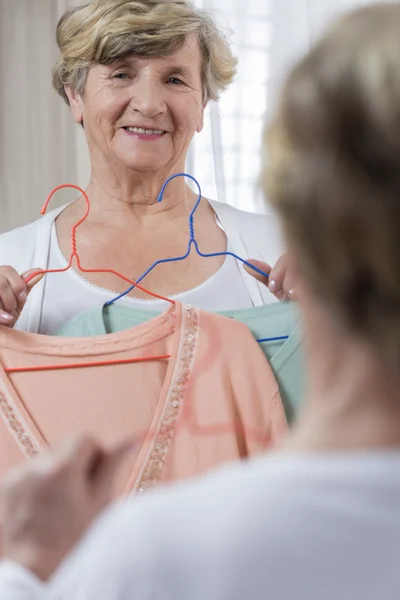 Senior woman choosing sweater — Stock Photo, Image