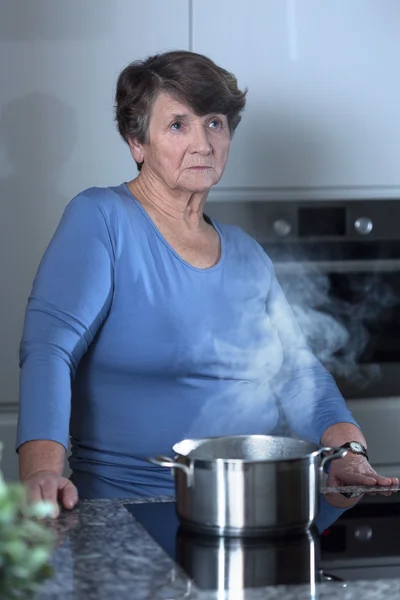 Worried grandma standing in the kitchen — Stock Photo, Image