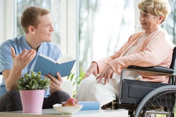 Care assistant reading book — Stock Photo, Image