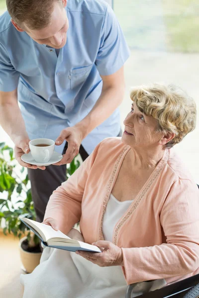 Caregiver helping disabled pensioner — Stock Photo, Image