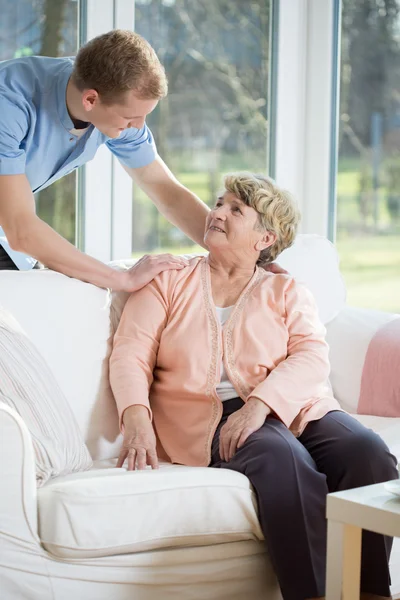 Enfermera masculina asistiendo a mujer jubilada — Foto de Stock