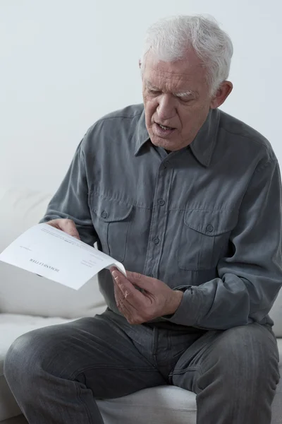 Пожилой человек читает неоплаченные счета — стоковое фото