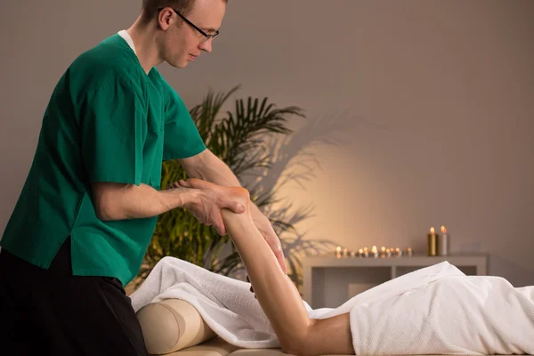 Massagista massageando membro inferior — Fotografia de Stock