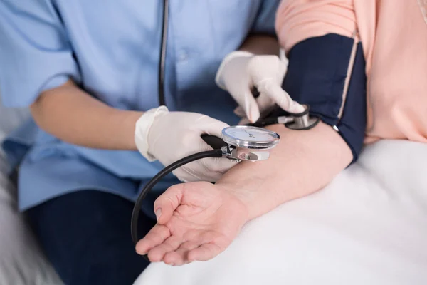 Enfermeira usando medidor de pressão arterial — Fotografia de Stock