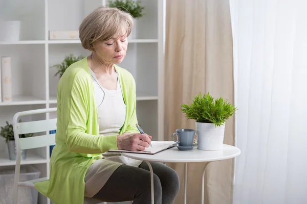 Volwassen vrouw wijzend in agenda — Stockfoto