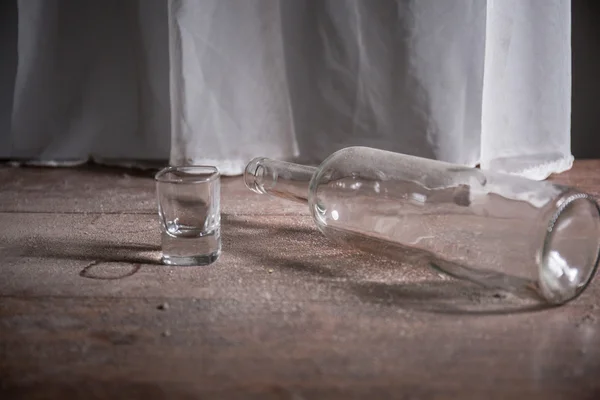 Flaska och glas på det smutsiga golvet — Stockfoto