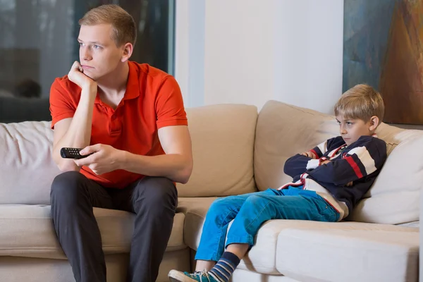 Bambino annoiato e padre sta guardando la TV — Foto Stock