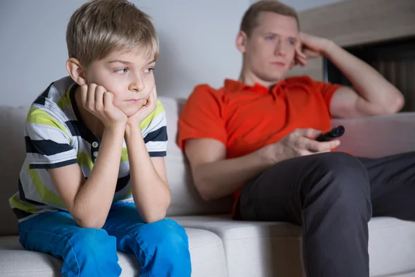 Aburrido niño con su padre sentado y viendo la televisión — Foto de Stock