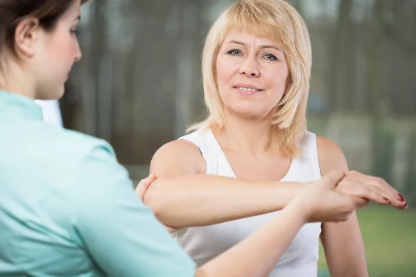 Physical therapist diagnosing painful arm — Stock Photo, Image