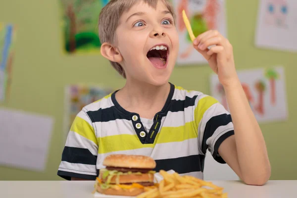 Felice ragazzo mangiare patatine fritte — Foto Stock