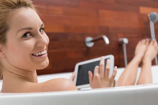 Kvinna med hjälp av Tablet PC i ett badkar — Stockfoto
