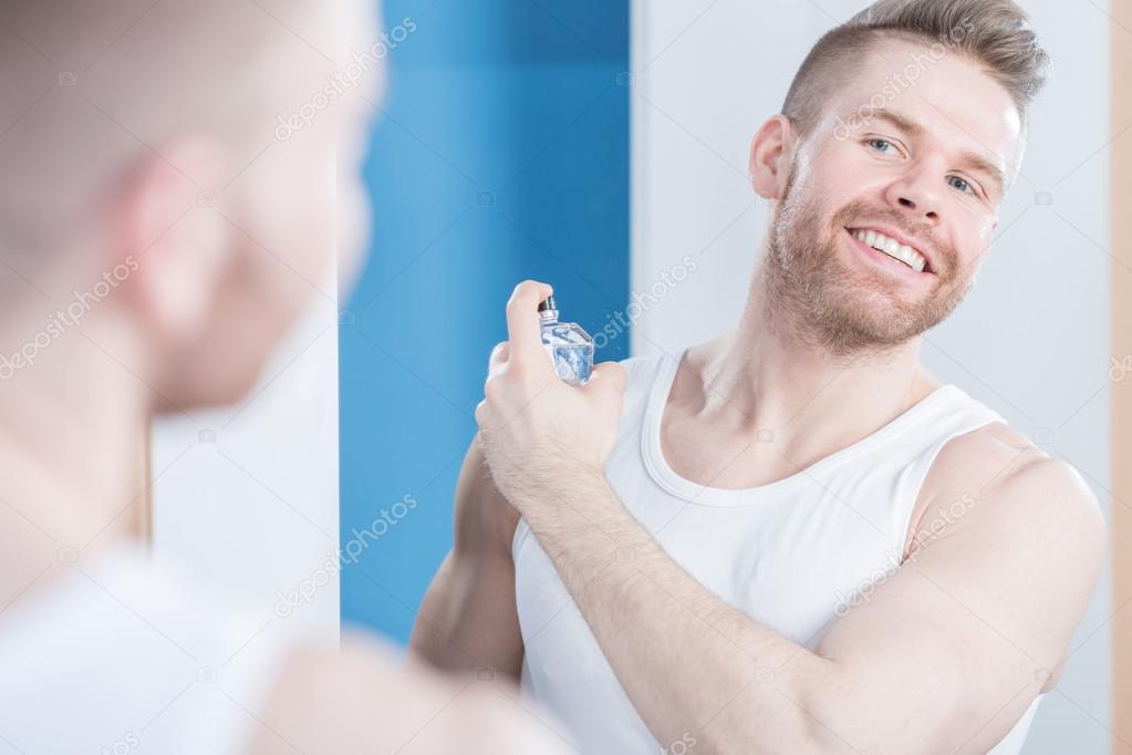Handsome guy applying perfume