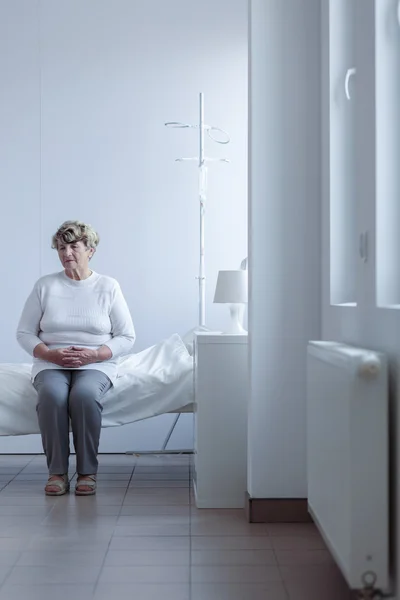 ผู้หญิงนั่งบนเตียงโรงพยาบาล — ภาพถ่ายสต็อก
