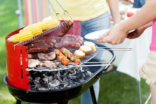 Host serving woman grilled sausages — Stock Photo, Image