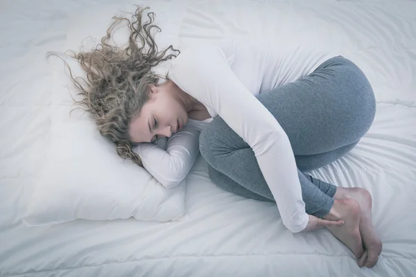 Femme enroulée dans son lit — Photo