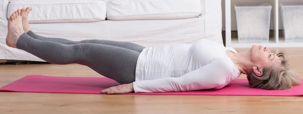 Vrouw verhogen benen tijdens yoga — Stockfoto