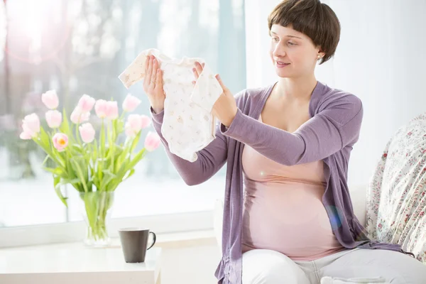 Mujer embarazada con ropa de bebé — Foto de Stock