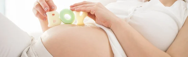 Femme tenant des lettres de jouet sur son ventre — Photo