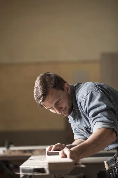 Carpenter sanding wooden plank — Stock Photo, Image