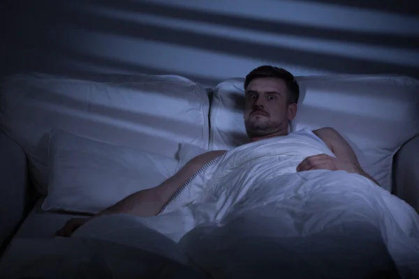 Przerażony mężczyzna w łóżku — Zdjęcie stockowe