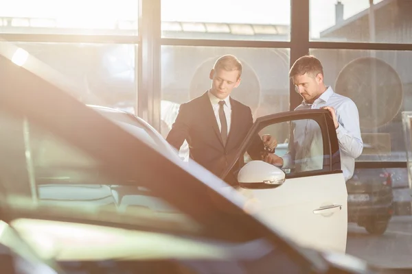 Businessman watching car in showroom — Stock Photo, Image