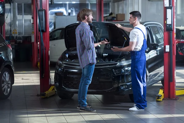 Automotive technician talking with client — Stock Photo, Image