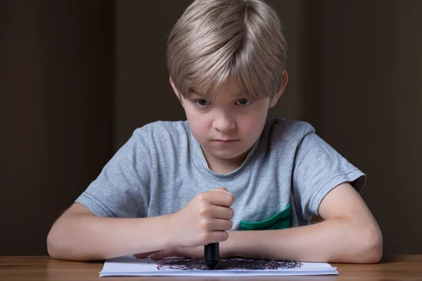 Unhappy child holding black crayon — Stock Photo, Image