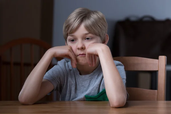 Незадоволений дитина сидить за столом — стокове фото
