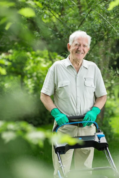 Elderly man mows a lawn — Stock Photo, Image