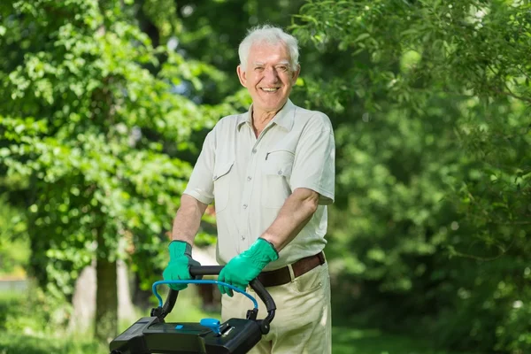 Elderly man mows a lawn — Stock Photo, Image