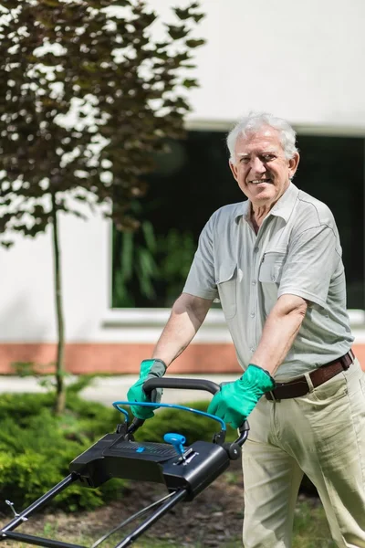 Elderly man mows a lawn — Stock Photo, Image