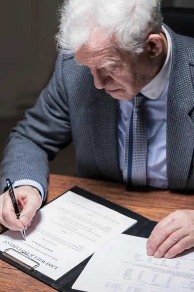 Старый бизнесмен подписывает контракт — стоковое фото