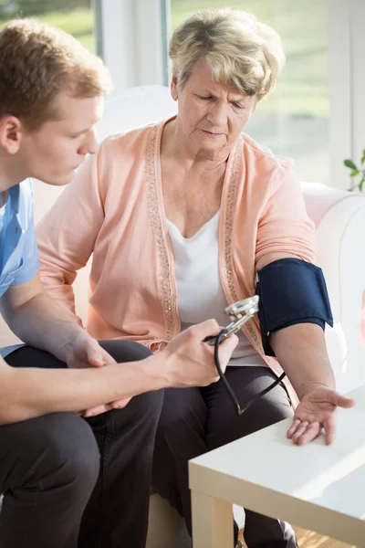 Male measures the pulse of an older woman — Stock Photo, Image
