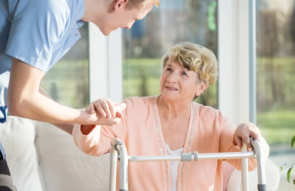 Man hjälper till att stå upp en äldre kvinna — Stockfoto