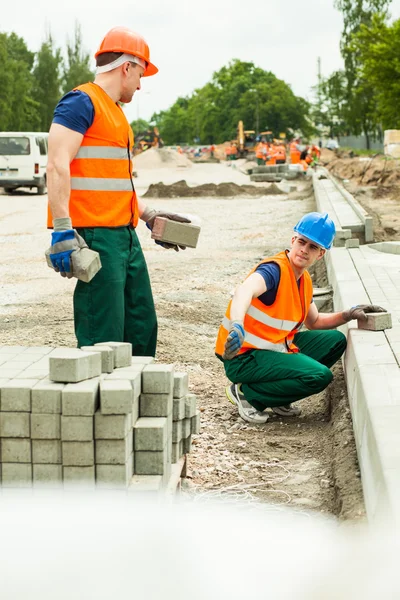 Werknemers in de bouw straatstenen installeren — Stockfoto