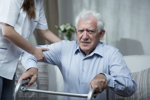 Fisioterapeuta ayudando a hombre mayor discapacitado — Foto de Stock
