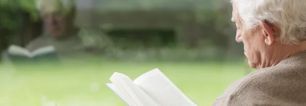 Pensativo hombre mayor leyendo libro — Foto de Stock