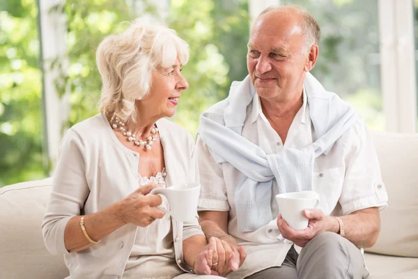 Elder couple holding cups — Stock Photo, Image