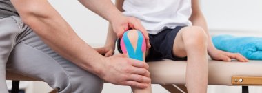 Physiotherapist applying kinesiology tapes clipart