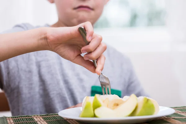 Недовольный мальчик ест яблоко — стоковое фото