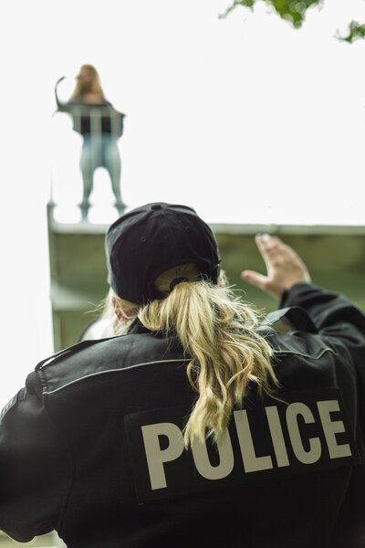 Женщина-полицейский с мегафоном, помогающая девушке
