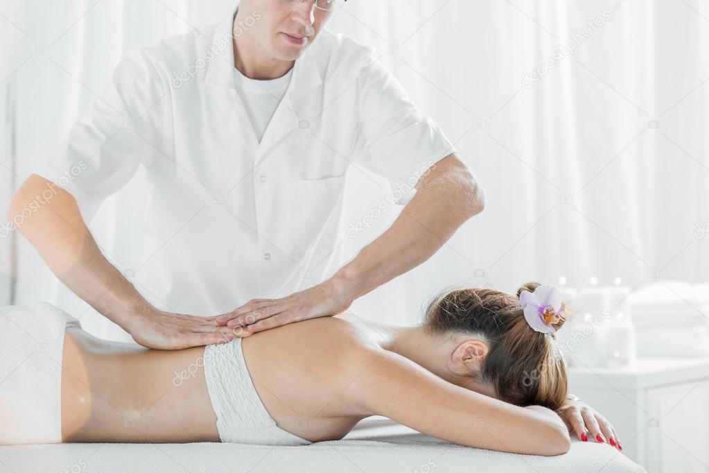 Professional masseur massaging womans back