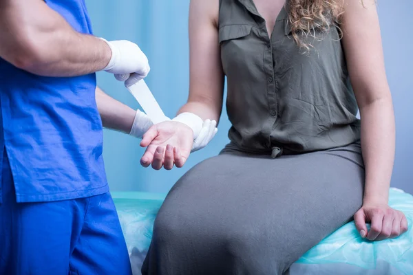 Emergency worker bandaging female hand — Stock Photo, Image