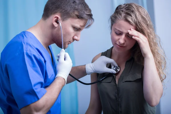 Doctor with stethoscope diagnosing patient — Stock Photo, Image
