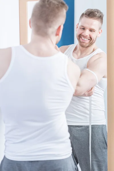 Muskulöser Mann misst seinen Bizeps — Stockfoto
