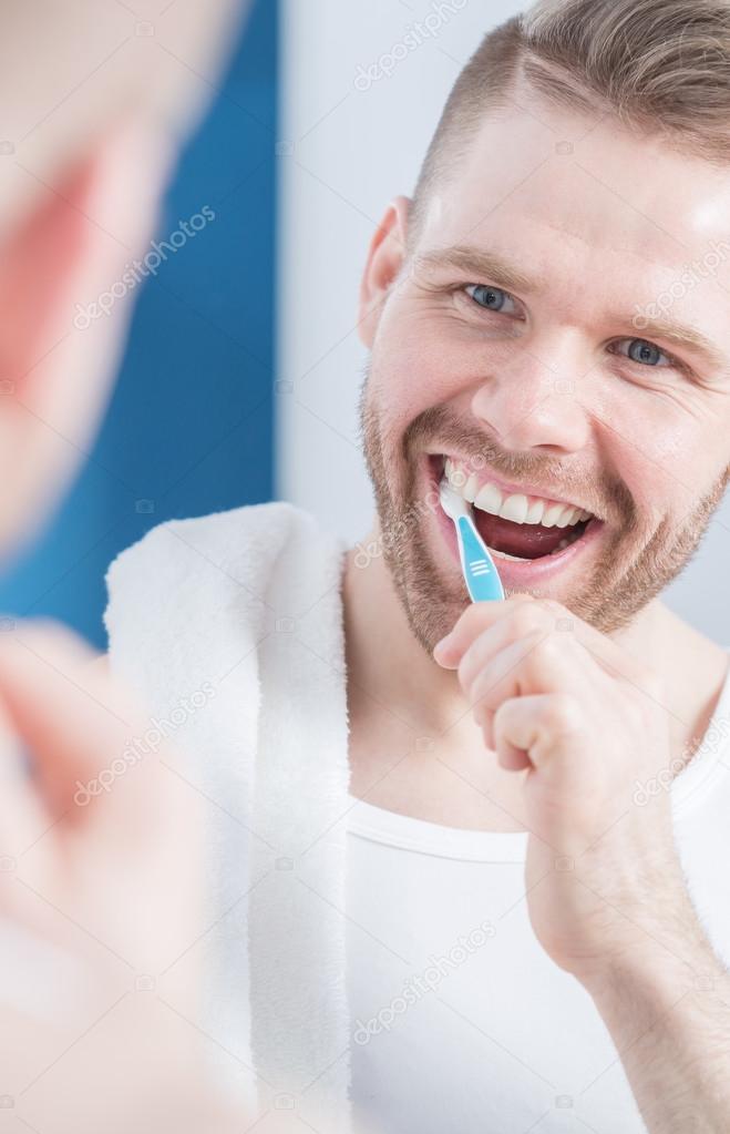 Smiling guy brushing teeth